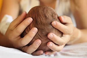 A loving caregiver cradling a babies head in her hands