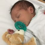 Premature baby sucking on a WubbaNub pacifier